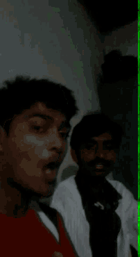 two young men are posing for a picture in a dark room