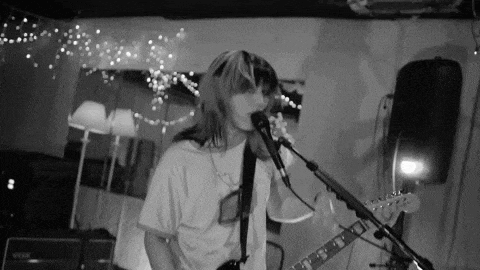 a woman is singing into a microphone while holding a guitar