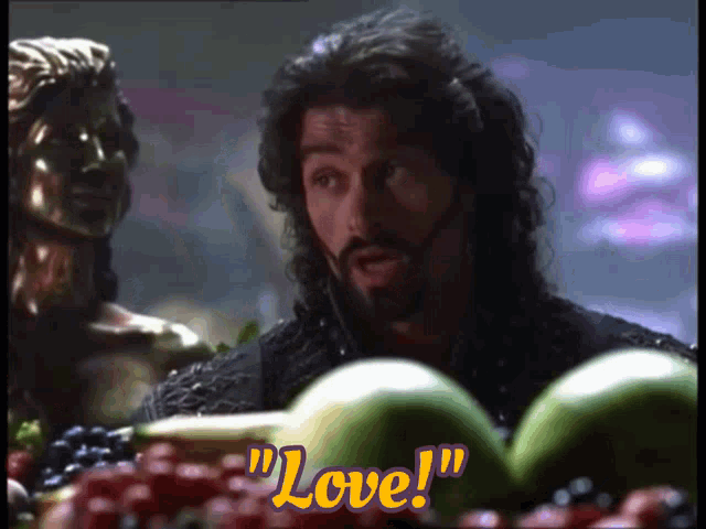 a man with a beard is surrounded by fruit and says love