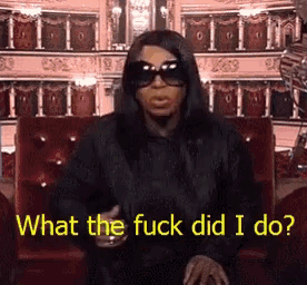 a woman wearing sunglasses is sitting on a red couch and says what the fuck did i do