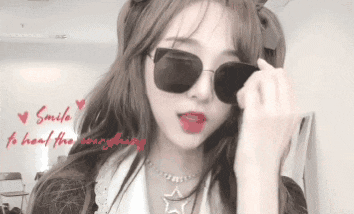 a girl wearing sunglasses and a necklace with the words smile to heal the world behind her