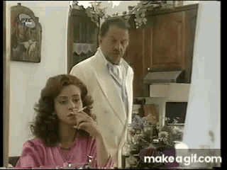 a man and a woman are sitting at a table smoking cigarettes .