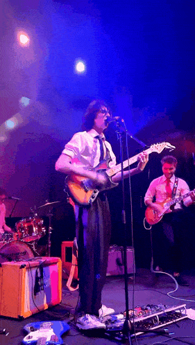 a man sings into a microphone while playing a guitar