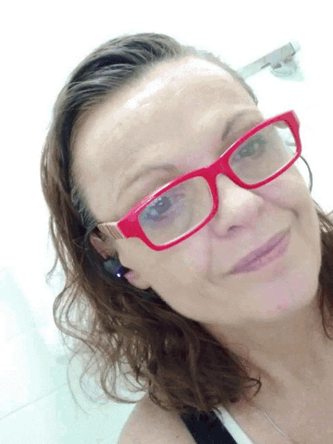 a woman wearing red glasses is smiling and looking at the camera
