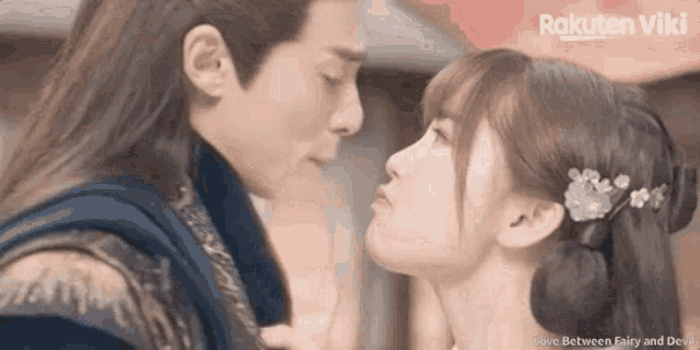 a man and a woman are kissing in front of a sign that says rakuten viki