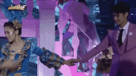a man in a purple suit and tie is dancing with a woman in a blue dress ..