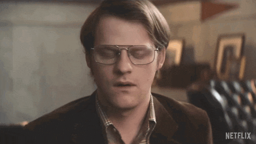 a close up of a man wearing glasses and a brown jacket with a netflix logo in the corner