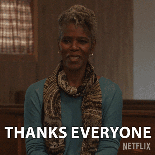 a woman wearing a scarf and a sweater says thanks everyone