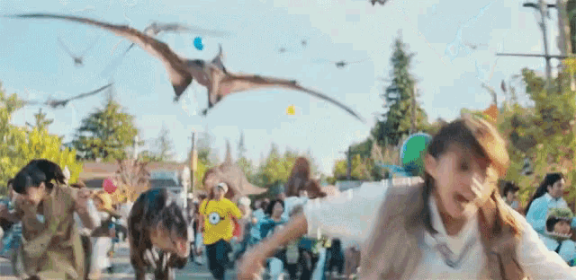 a group of people are running away from dinosaurs in a park
