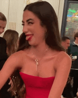 a woman in a red strapless dress is sticking out her tongue .