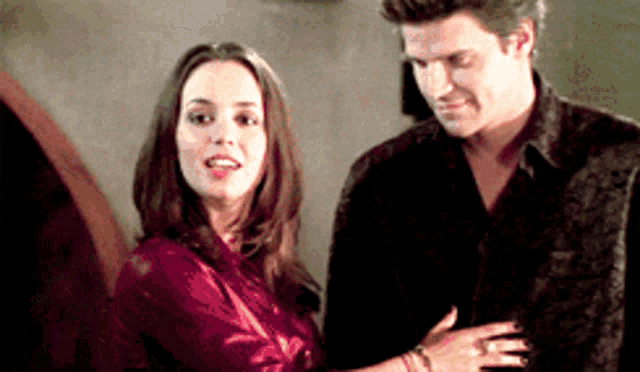 a man and woman are standing next to each other and the woman is wearing a red shirt