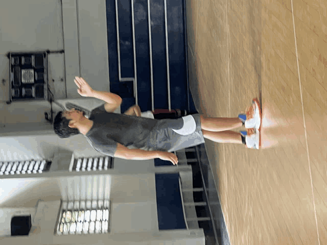 a man is standing on a wooden floor in front of a scoreboard
