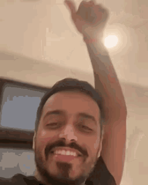 a man with a beard is smiling and giving a thumbs up sign .