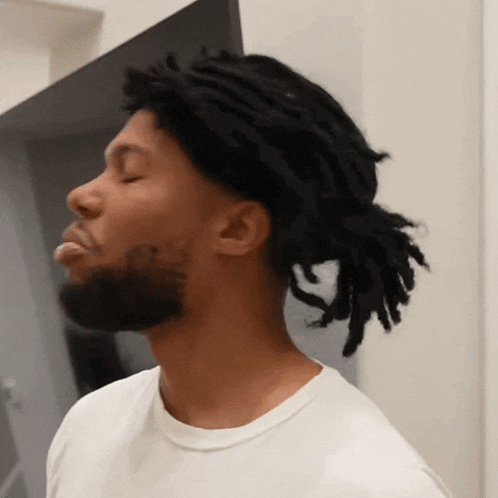 a man with dreadlocks and a beard is wearing a white t-shirt