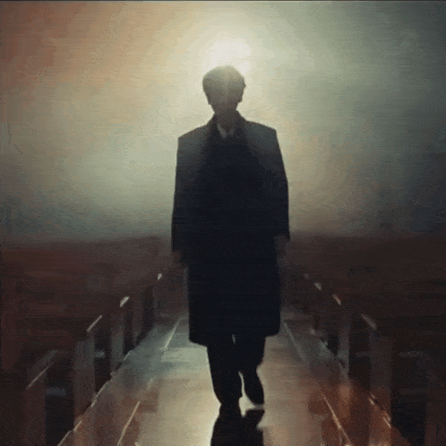 a man in a suit and tie is walking down a dark hallway .