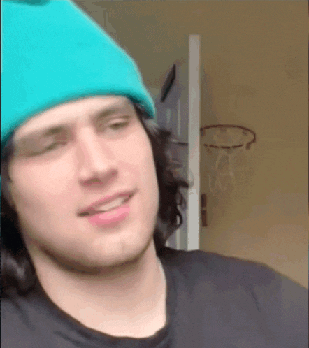 a man wearing a blue hat and black shirt is smiling