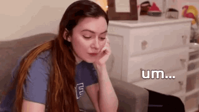 a woman is sitting on a couch with her hand on her face and talking on a cell phone .