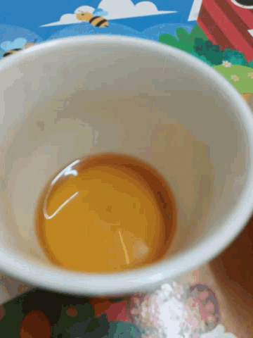 a white cup with a yellow liquid in it on a table