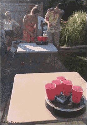 a group of people standing around a table with red cups