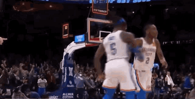 two basketball players are standing next to each other in front of a crowd .