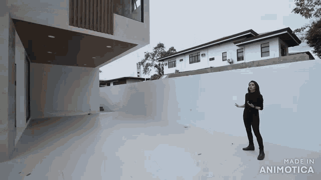 a woman is standing in front of a white building with the words made in animotica on the bottom
