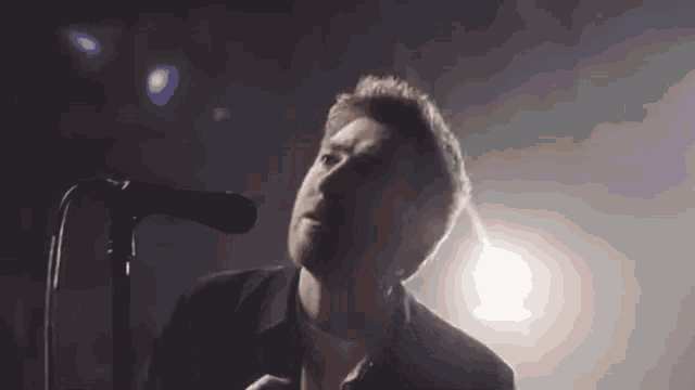 a man singing into a microphone with a shadow on his face