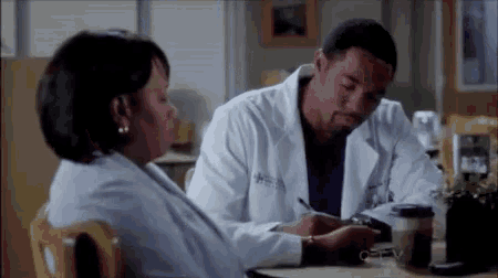 a man and a woman are sitting at a table with a cup of coffee .