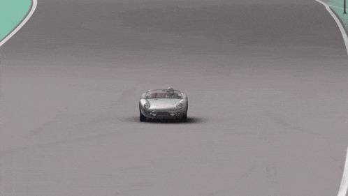 a car is driving on a race track with a wall that says project on it