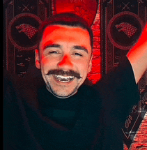 a man with a mustache and a black shirt is smiling with his arms in the air .