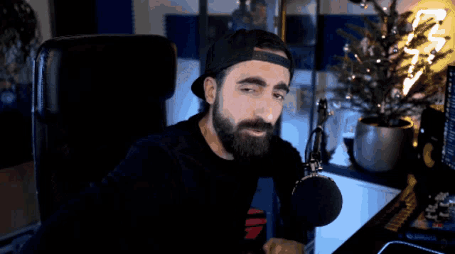 a man with a beard is sitting in front of a microphone in front of a computer