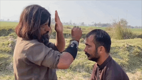 a man with a beard is giving another man a high five .