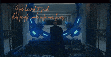 a man in a black coat is standing in front of a blue ring with the words i 've heard it said