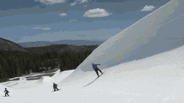 a man in a blue jacket is riding a snowboard down a snowy hill