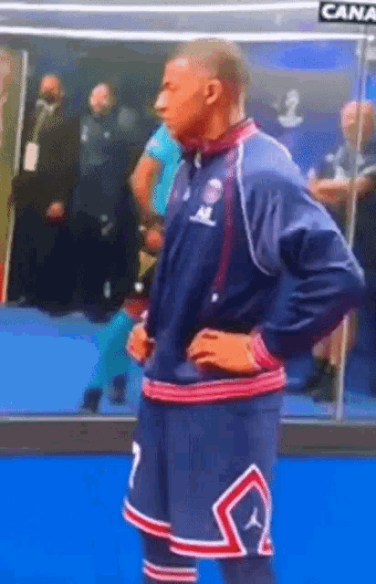 a man in a basketball uniform with the number 7 on his shorts is standing with his hands on his hips .