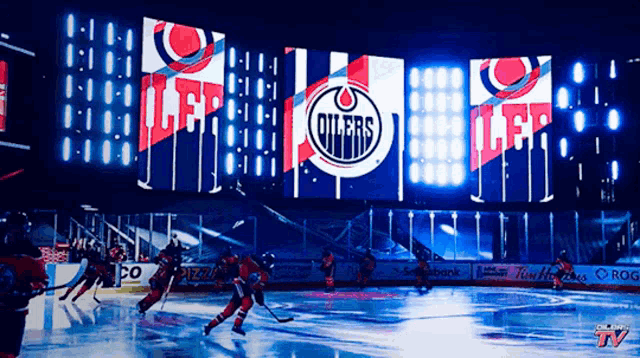a hockey game is being played in front of a large screen that says oilers on it