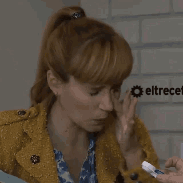 a woman in a yellow jacket is eating something from a person 's hand
