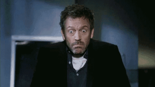 a man in a suit is making a funny face with his eyes wide open .