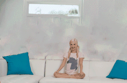a girl is sitting on a couch in front of a wall with cartoon cats on it
