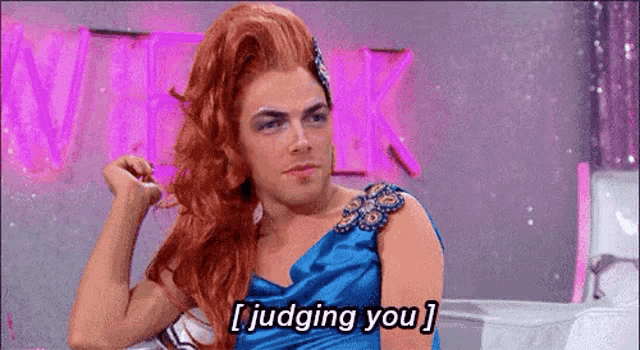 a drag queen is sitting on a couch and saying i judging you