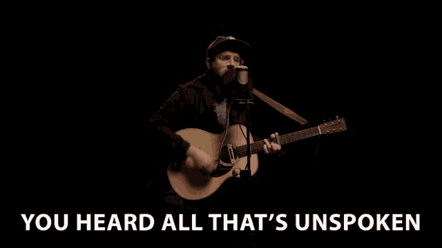 a man singing into a microphone with the words you heard all that 's unspoken above him