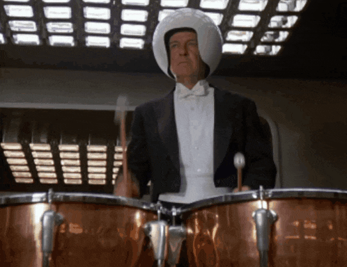 a man in a tuxedo is playing a drum set