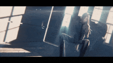 a woman is sitting in a dark room with a window behind her