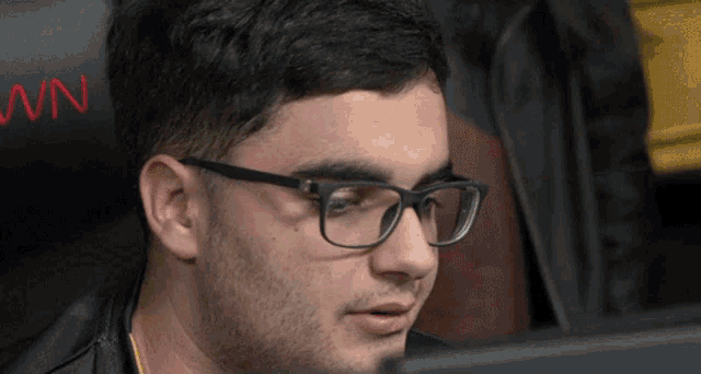 a man wearing glasses is looking at a computer screen with the letter n on the back of the chair