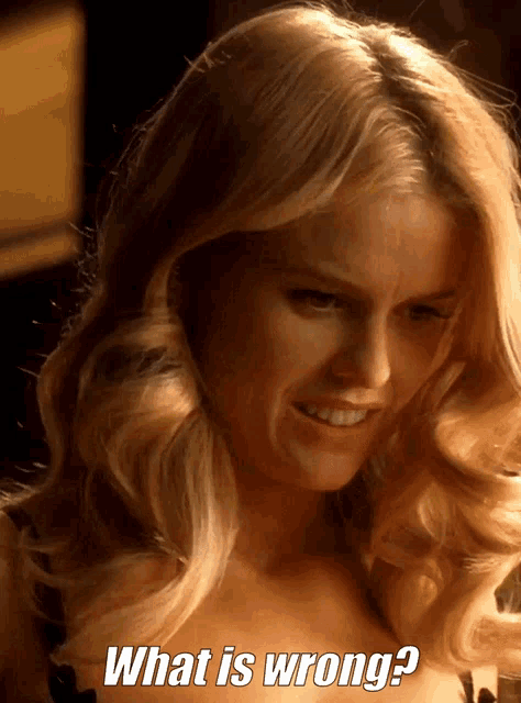 a woman with blonde hair is smiling and asking " what is wrong "