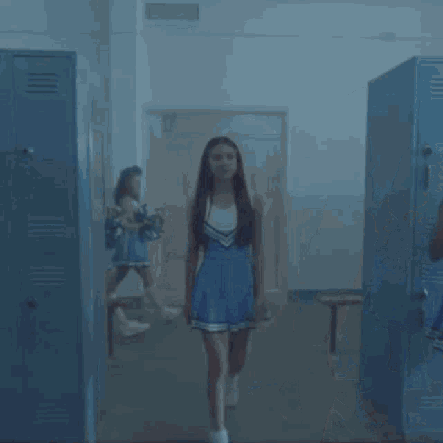 a group of cheerleaders are standing in a locker room talking .