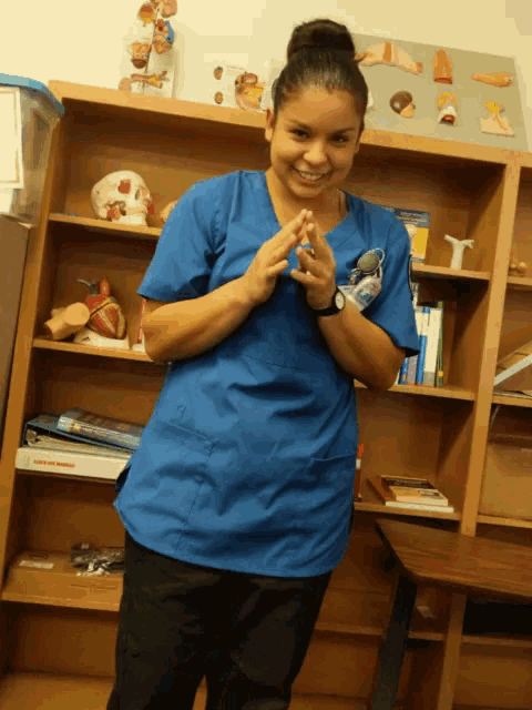 a woman wearing a blue scrub top is smiling