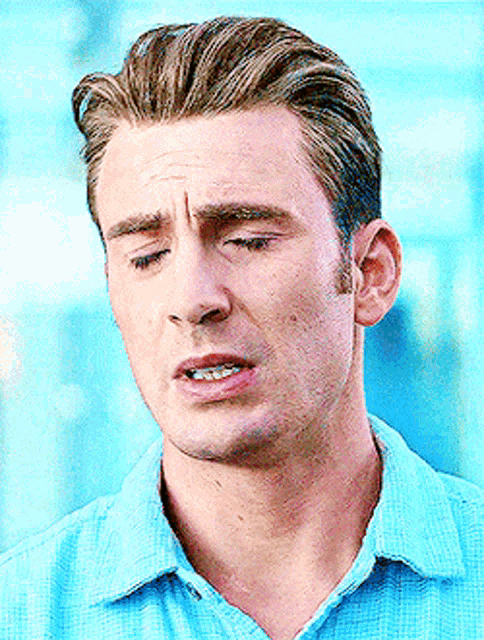 a close up of a man 's face with his eyes closed wearing a blue shirt