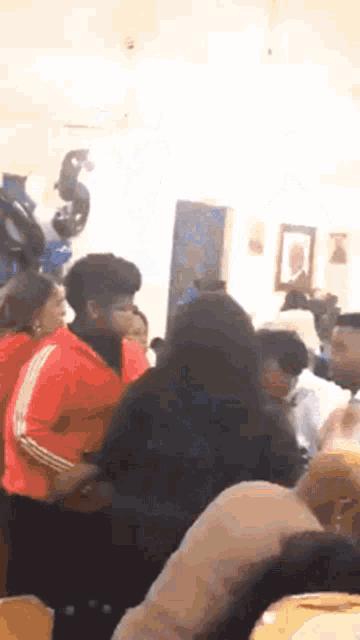 a group of people are dancing in a room with balloons in the background .