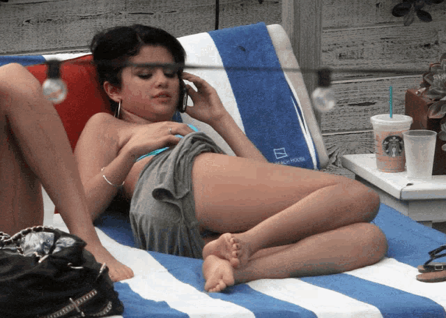 a woman laying on a lounge chair with a starbucks cup on a table