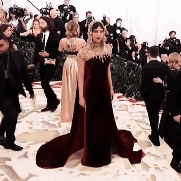a woman in a red and gold dress is standing in front of a crowd of people